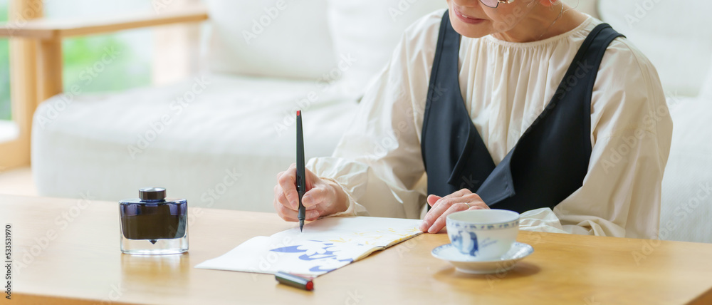 リビングで手紙を書くシニア女性