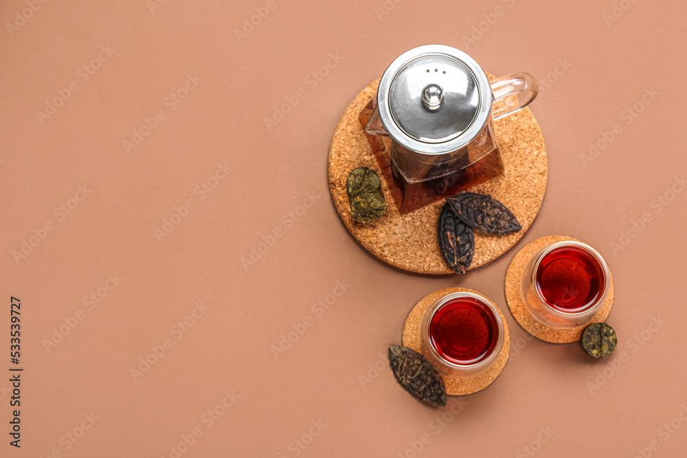 Teapot with glasses on puer tea on brown background