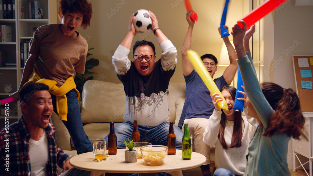 快乐的亚洲人和朋友在电视上看足球，在家庆祝胜利，w