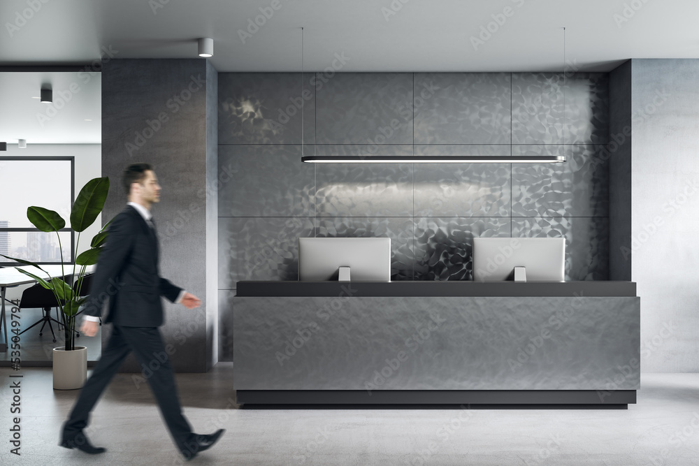 商人走过灰色办公室时尚的深色家具接待区的侧视图