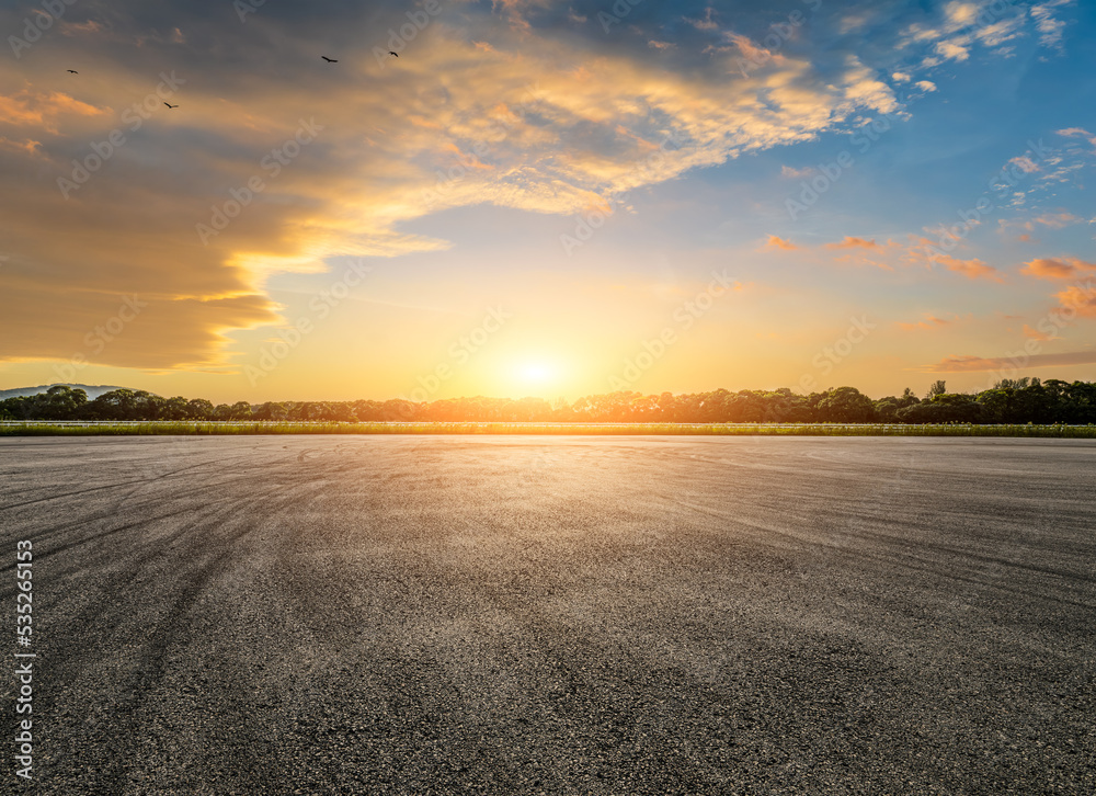 Empty asphalt race track road and green forest with sky clouds at sunset