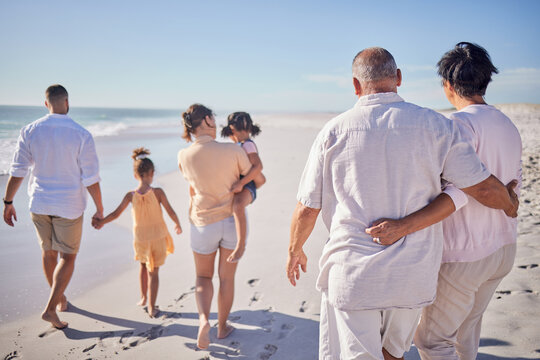 Big family at beach, relax on summer vacation with grandparents and kids at the sea. Retirement time together, quality travel in the sun and enjoy a holiday by the ocean. Sand, sunshine and fresh air