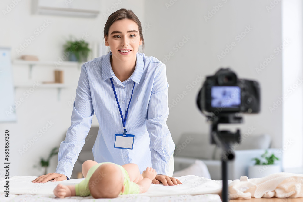 带着小婴儿的年轻女子在家录制视频课程