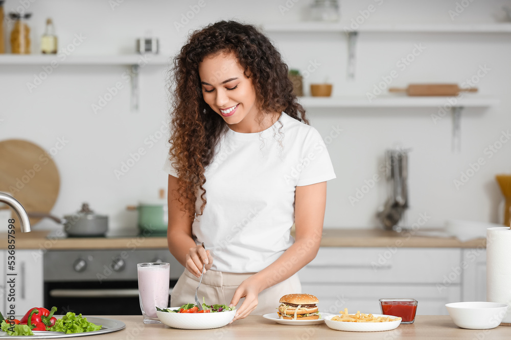 厨房里有健康和不健康食物的年轻非裔美国女性。饮食理念