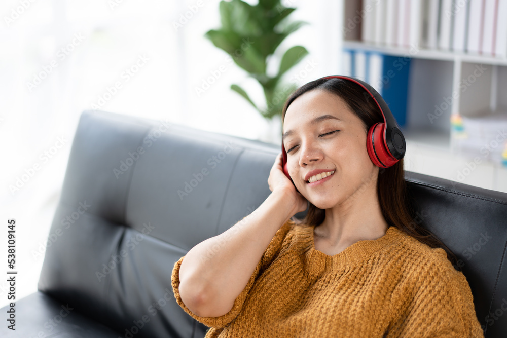 一位快乐的年轻亚洲女性用音乐应用程序的无线耳机听音乐的肖像