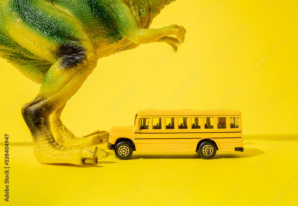 黄色背景上有校车的巨型玩具霸王龙。
