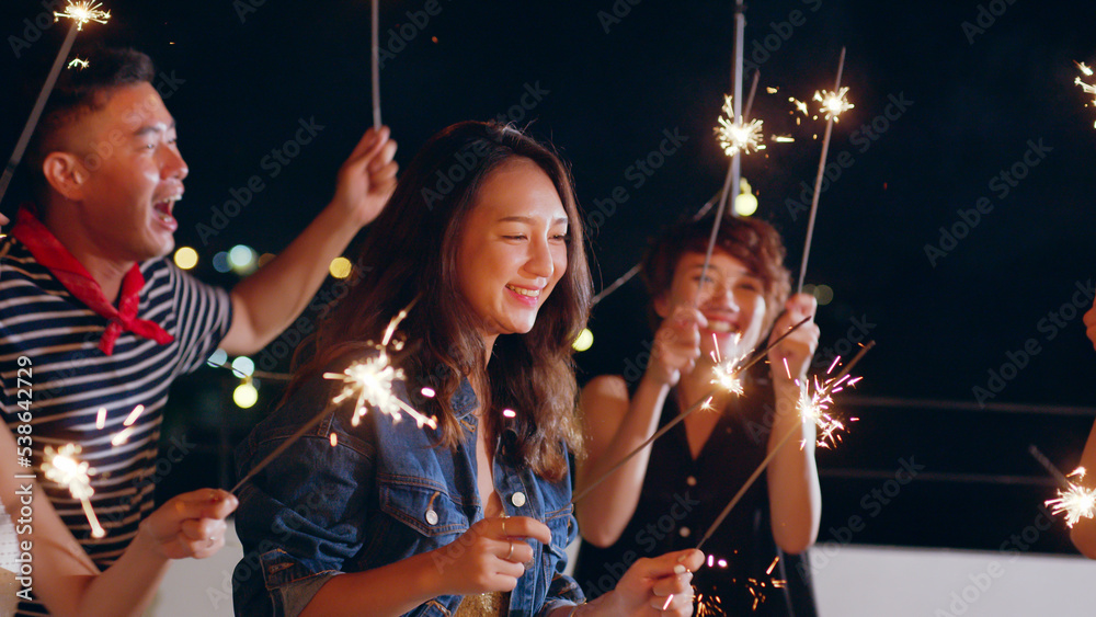 Group of young Asian people with friends celebrating party on rooftop holding sparklers fireworks an