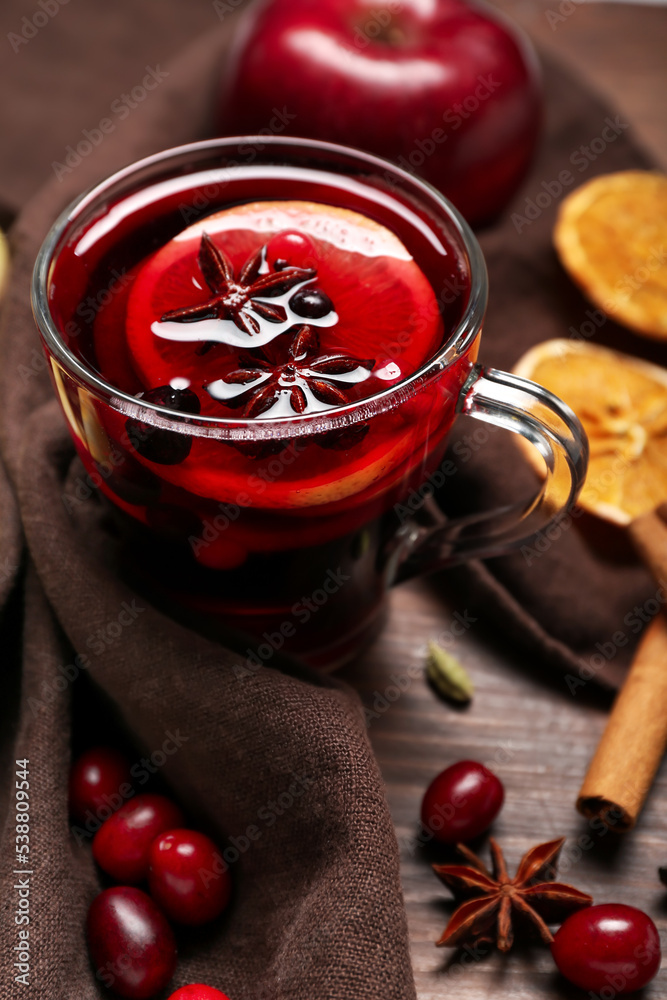 Cup of aromatic mulled wine on wooden table, closeup