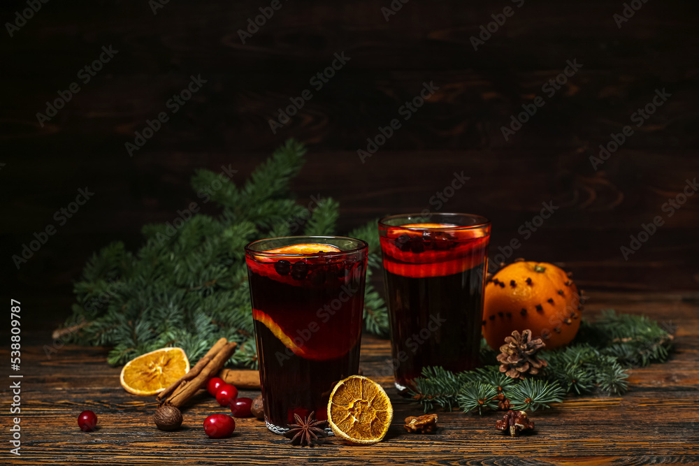 木桌上的一杯芳香的热葡萄酒、香料和冷杉枝