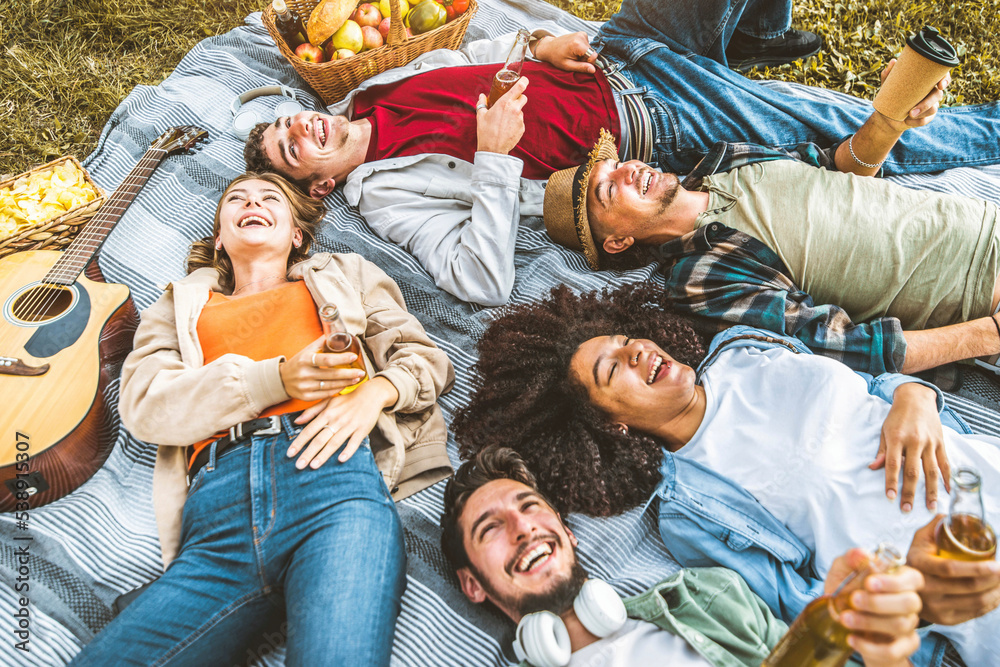 Friends group having fun together lying on the grass - Young people having picnic camping outdoor - 