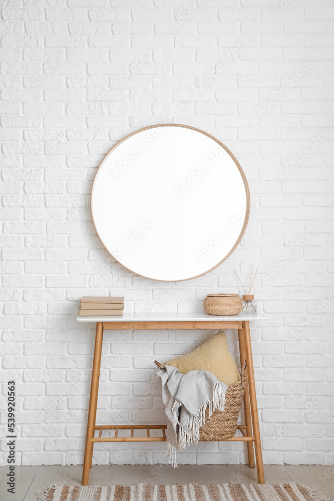 白色砖墙上挂着书、篮子和镜子的桌子