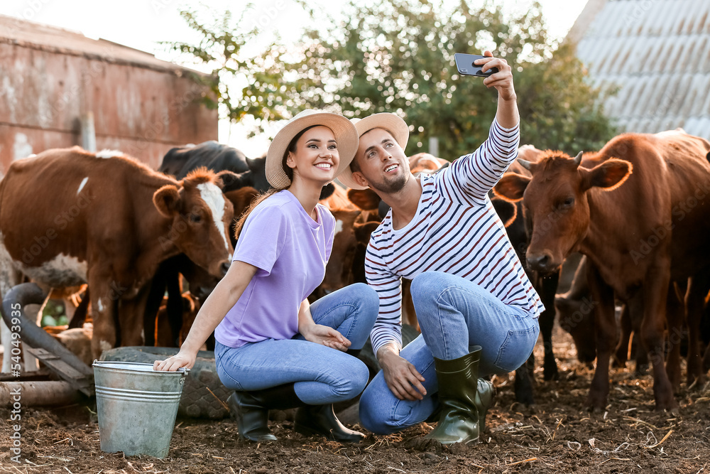 Young farmers taking selfie in paddock with cows outdoors