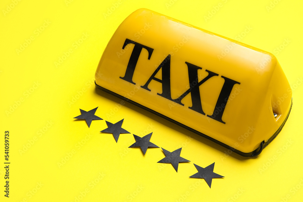 Taxi roof sign and paper stars on yellow background