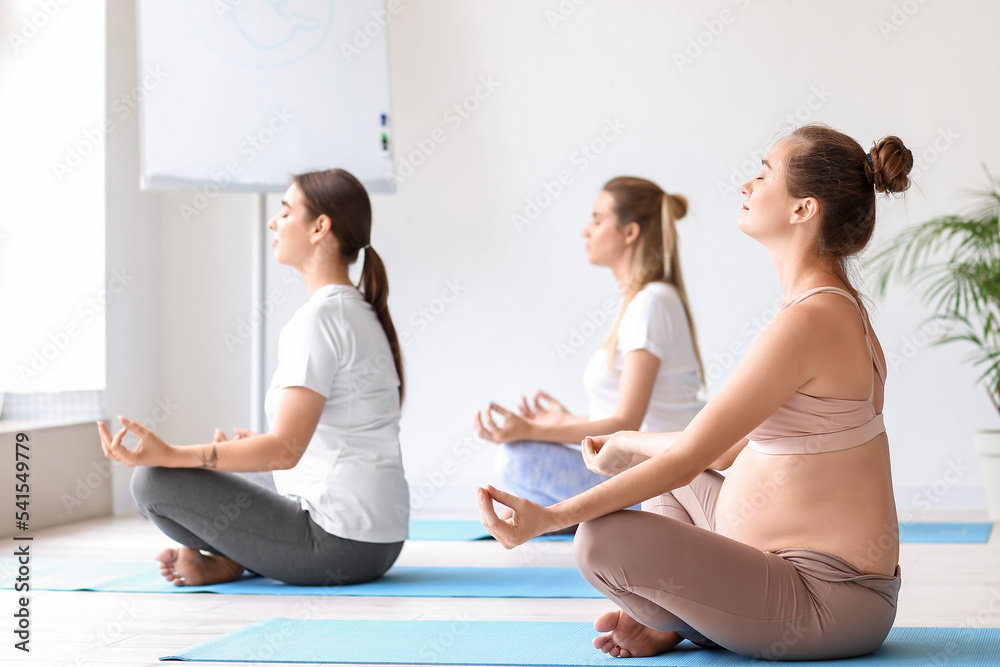 Young pregnant women doing yoga in gym
