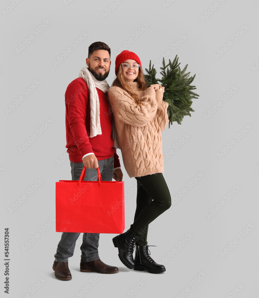 灰色背景带圣诞树和购物袋的年轻情侣