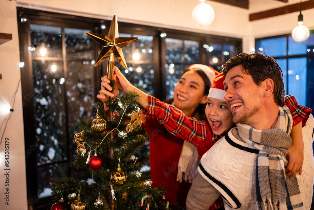 高加索夫妇和年幼的女儿在家里装饰圣诞树。