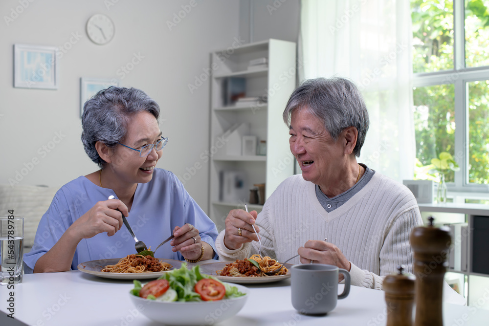 幸福的亚洲老年夫妇在家里的厨房里一起吃饭。退休老年夫妇生活方式