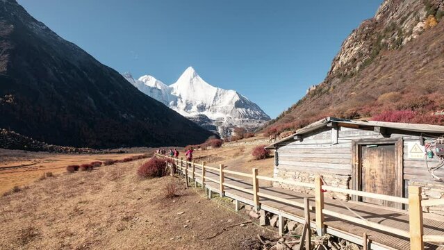 Tourists trekking in Xizangan valley with Yangmaiyong holy mountain on autumn in Yading nature reserve