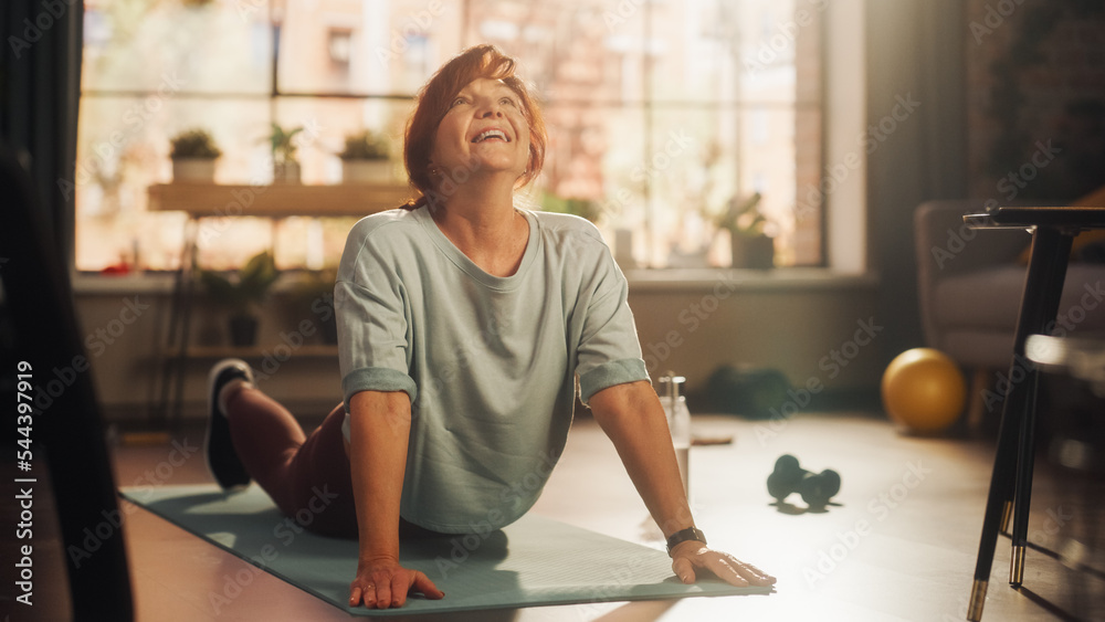 健康运动型中年女性在瑜伽垫上训练，做背部拉伸和核心力量训练