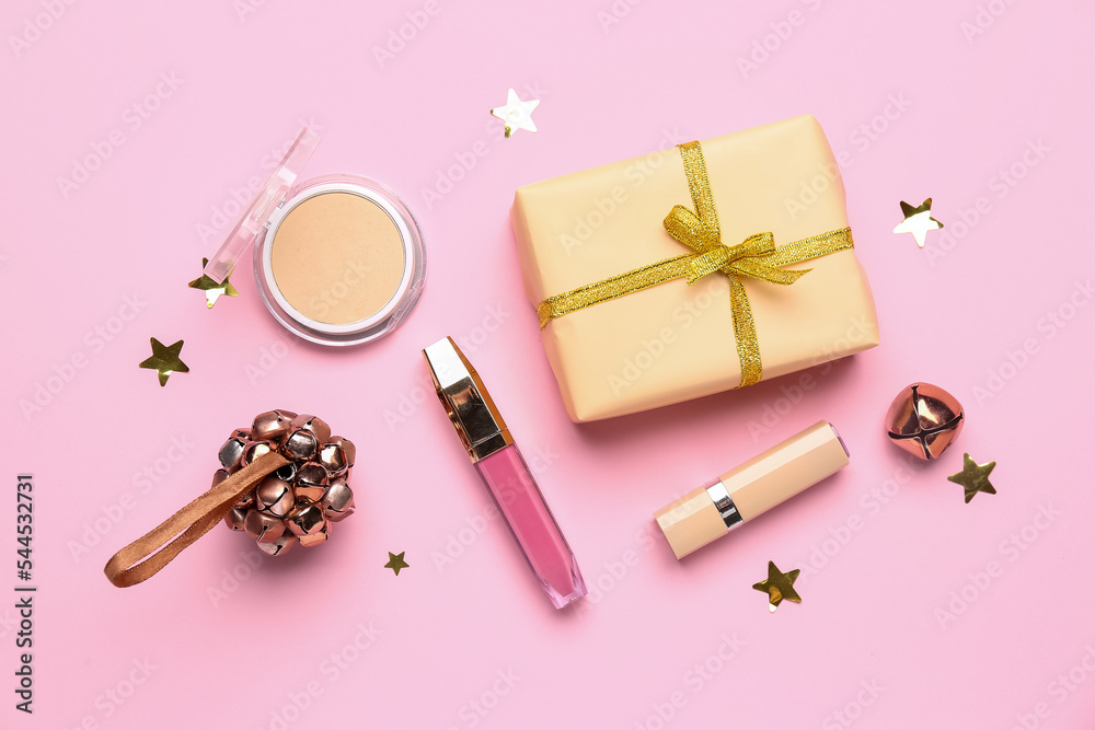 粉色背景带有圣诞铃铛和礼物的化妆品