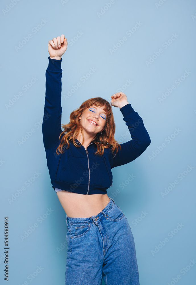 快乐的年轻女人穿着短上衣和牛仔裤在工作室跳舞，玩得很开心