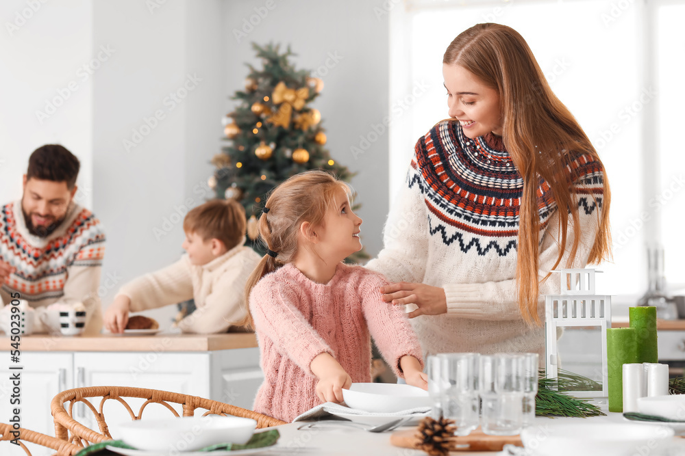 圣诞节前夕，小女孩和妈妈在厨房里摆餐桌