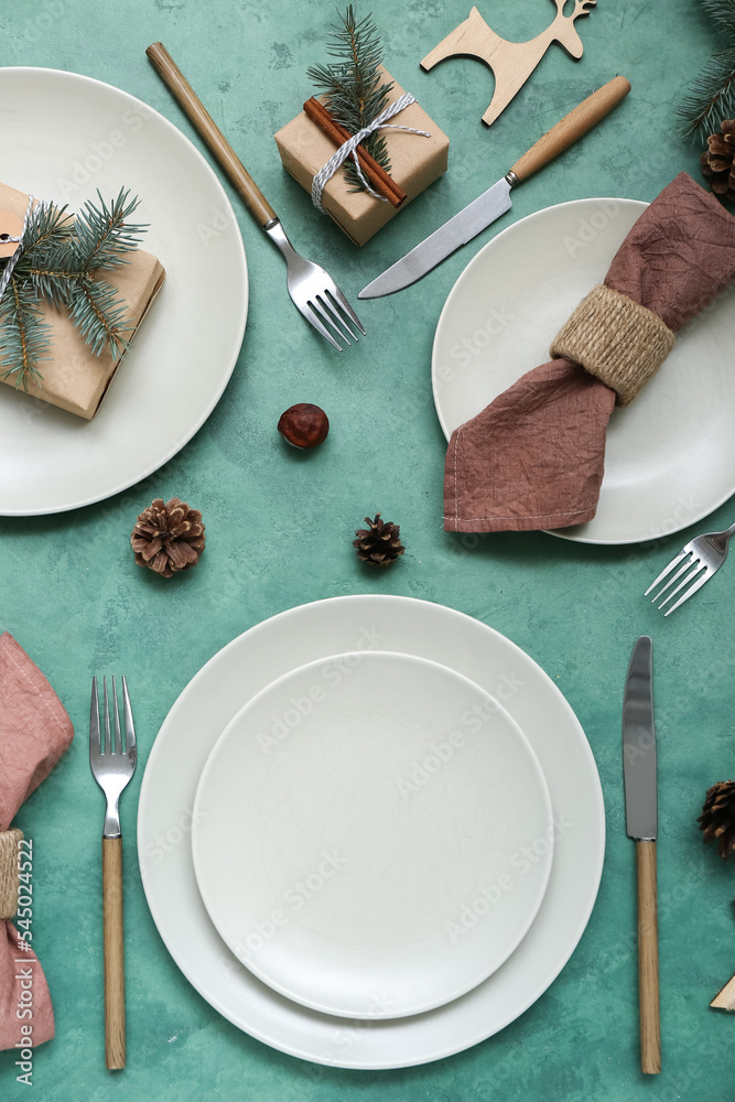 美丽的餐桌布置，绿色背景上有圣诞装饰、松果和礼物