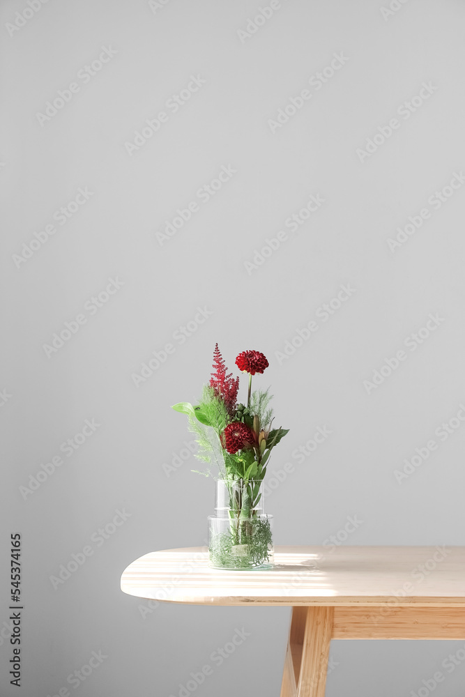 灰色墙壁附近的桌子上放着漂亮的插花花瓶