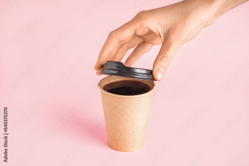 女人在粉红色背景下合上一杯咖啡