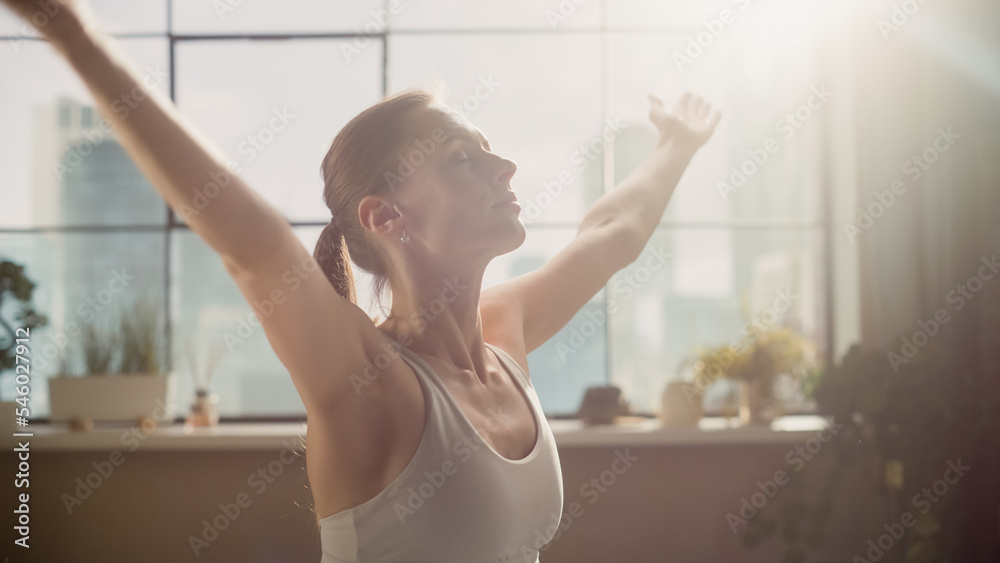 年轻的运动女性在阳光明媚的客厅里锻炼，早上练习冥想