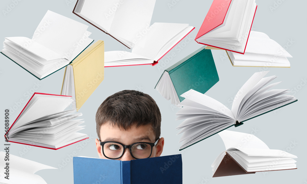 Little schoolboy and many flying books on light background