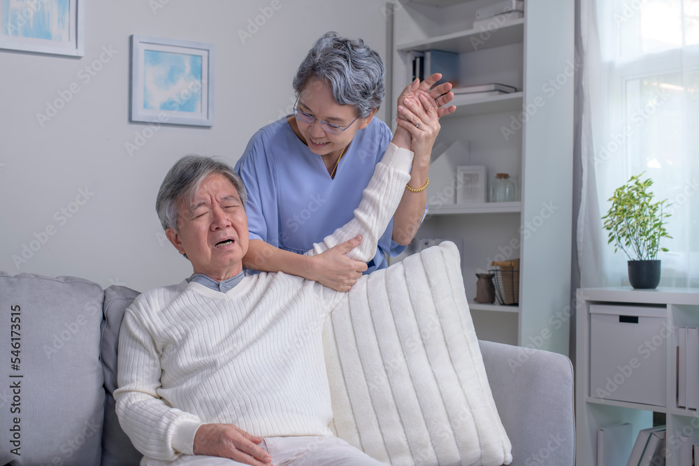亚洲老年丈夫坐在沙发上有背痛和肩膀疼痛的问题
