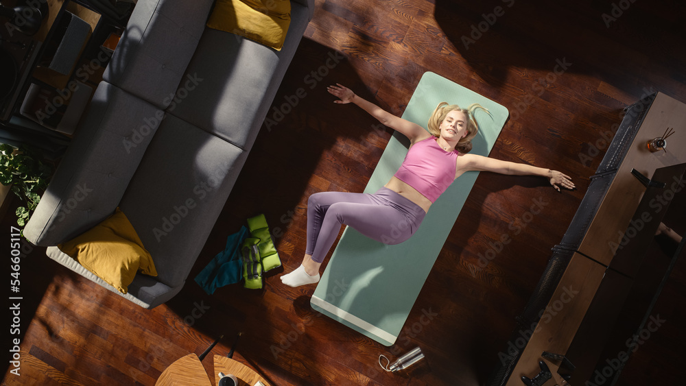 家庭锻炼的俯视图：华丽的女孩在家里的垫子上做躯干扭转拉伸运动。适合