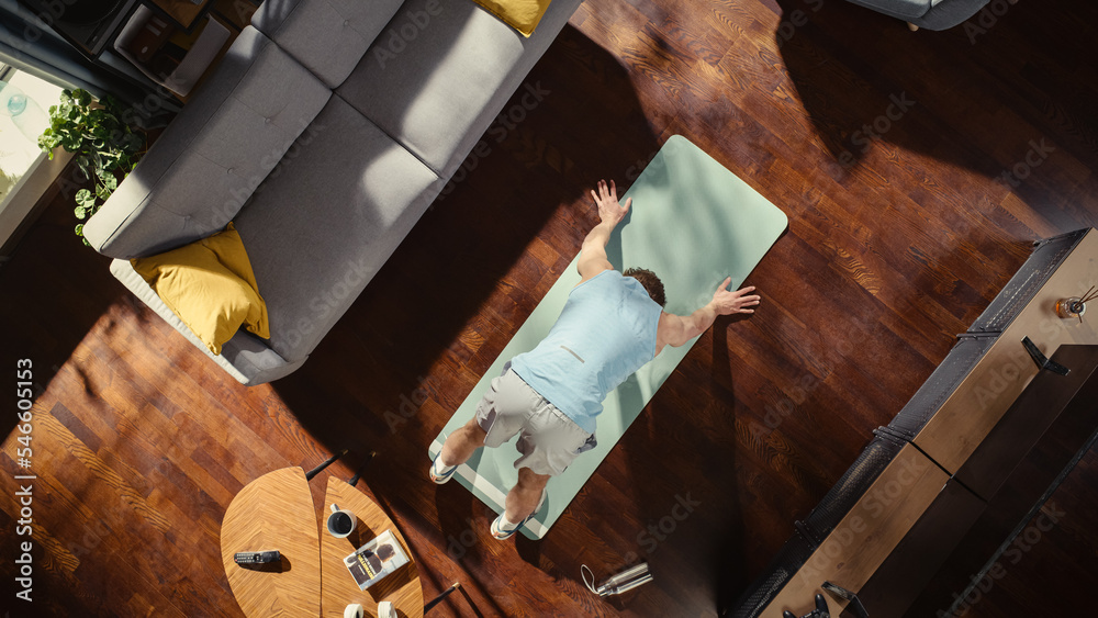 俯视运动：华丽的家伙在家里的运动垫上做瑜伽拉伸。肌肉发达，身体健康，双手