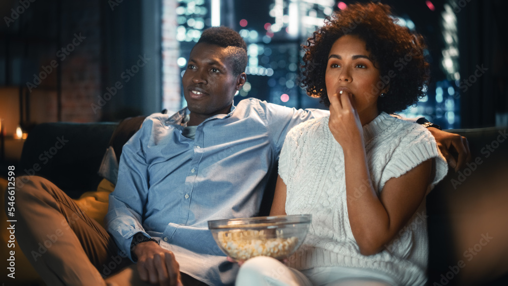 Black Woman Watches New Movie and Eating Popcorn at Home in Stylish Loft Apartment. African American