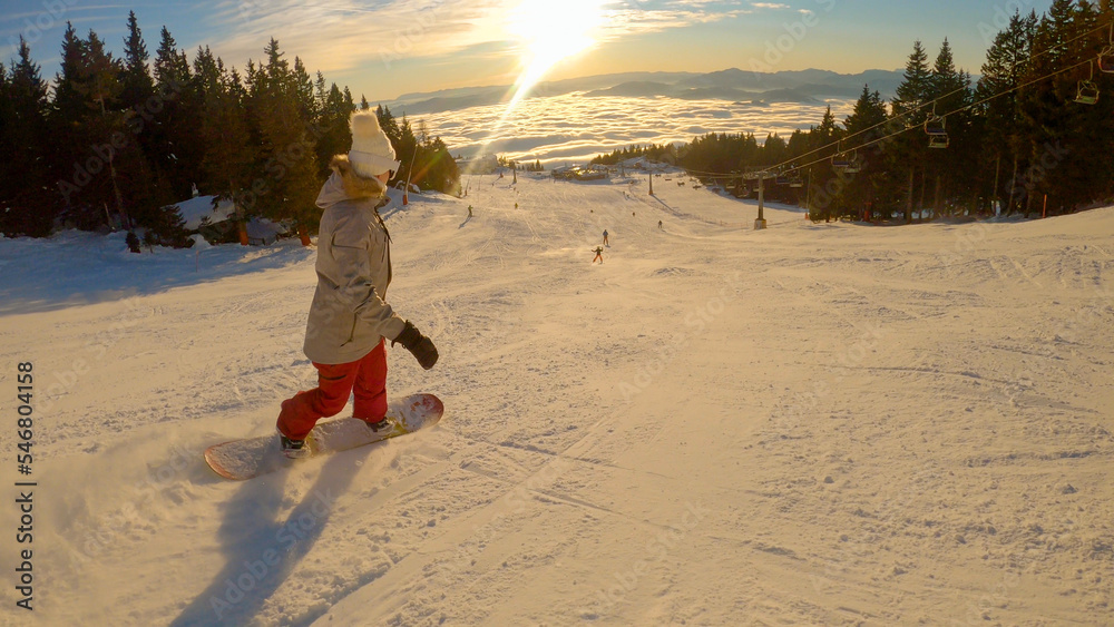 一个阳光明媚的冬日，一名女子带着滑雪板在山上骑行下坡