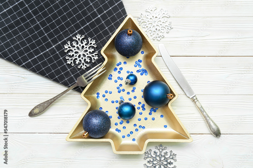 圣诞树形状的盘子，白色木质背景上有装饰、餐巾和餐具