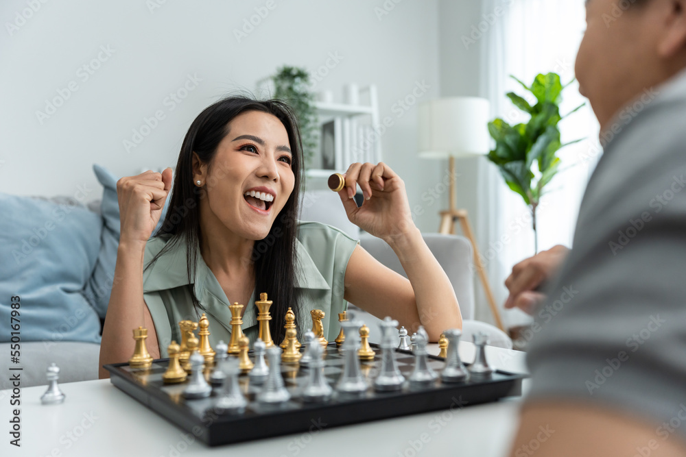 Asian attractive couple playing chess game in living room at home. 