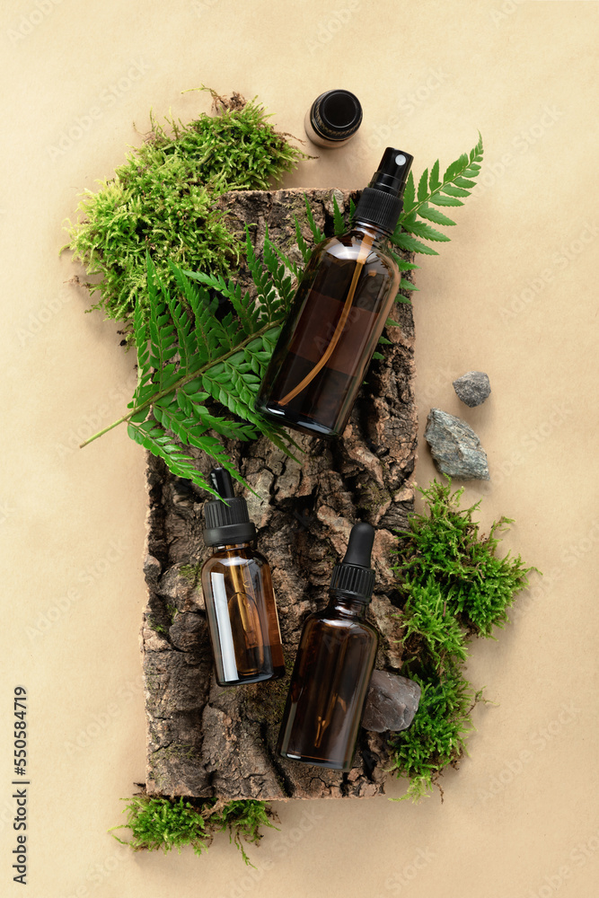 天然米色背景、树枝上的天然苔藓、树皮上的无标签化妆品瓶。护肤