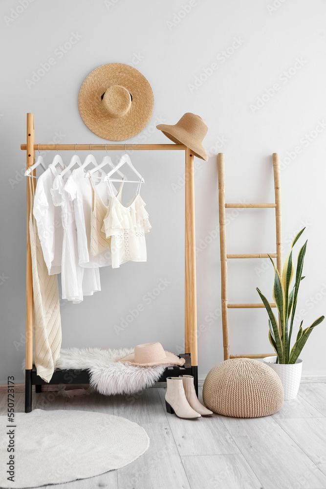 Interior of light dressing room with rack, clothes and ladder