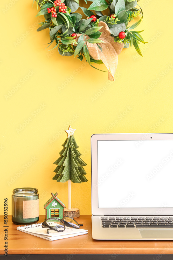 黄色墙壁附近桌子上放着圣诞玩具和蜡烛的笔记本电脑