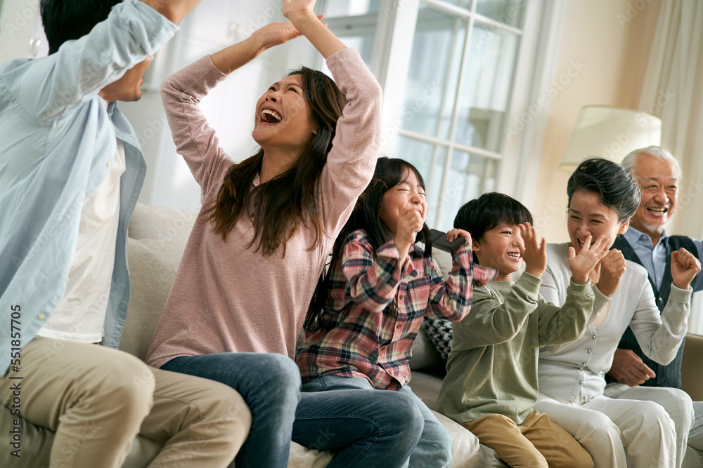 亚洲三代家庭在家一起看电视转播的足球比赛