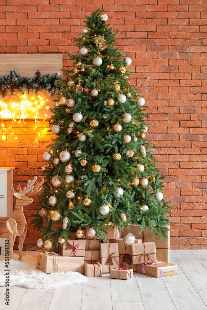 Glowing Christmas tree with presents and wooden reindeer near brick wall