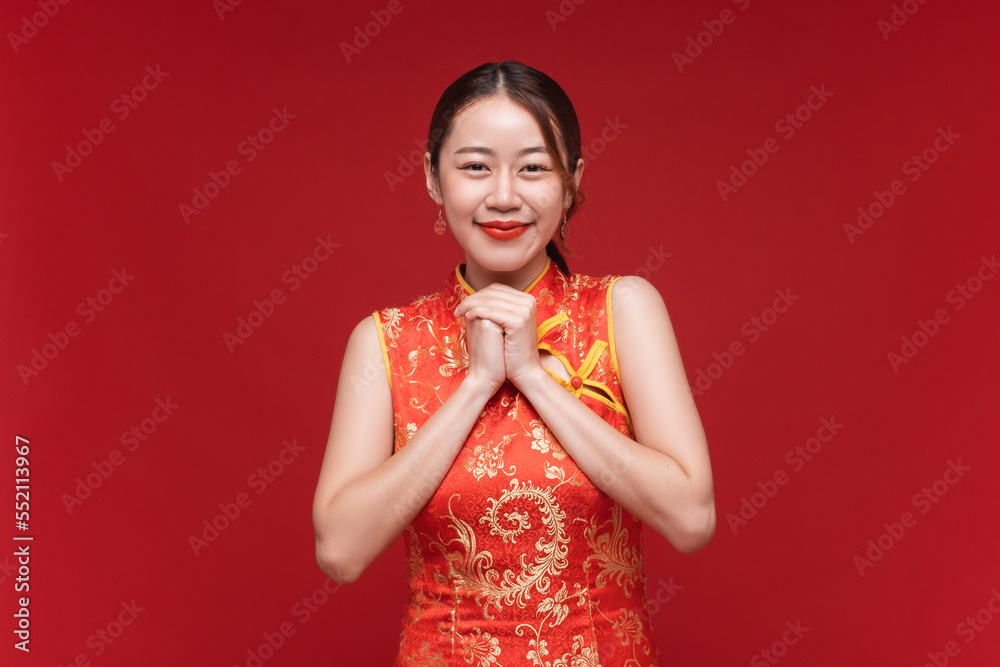 年轻的亚洲女人穿着奇装异服在红底上为中国新年许下愿望