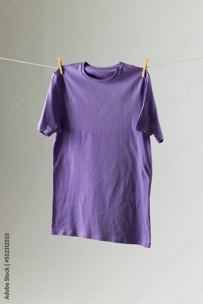 悬挂的紫色T恤和白底复制空间的特写