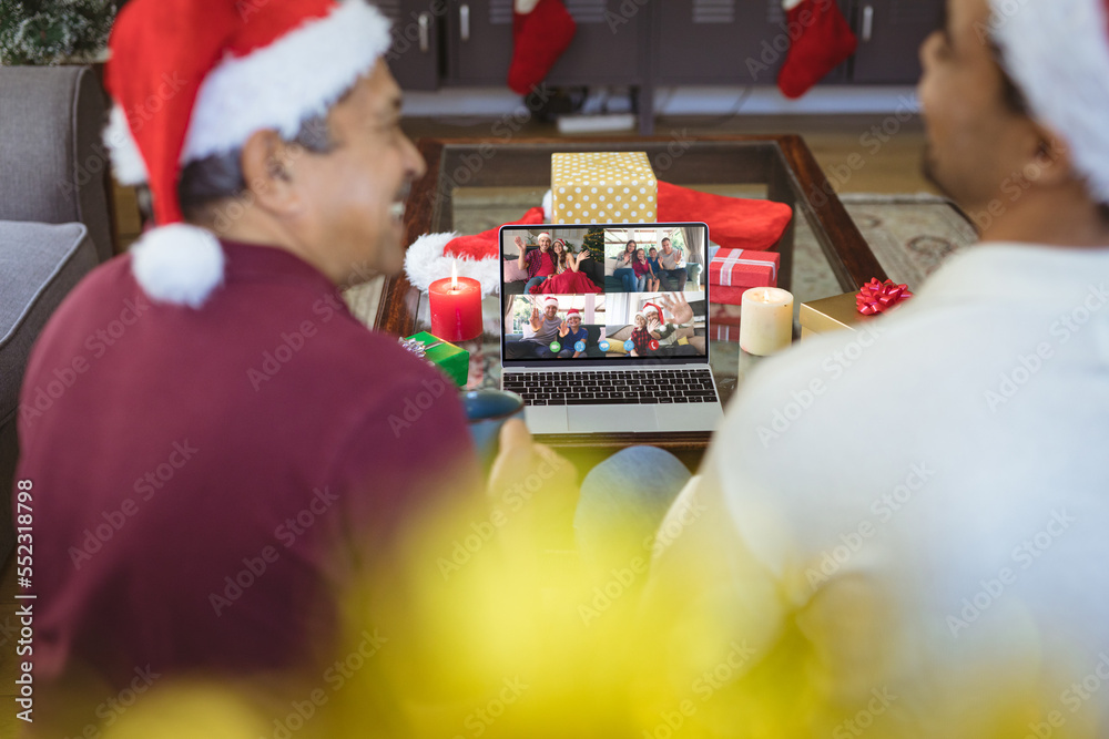 Senior biracial man and his adult son having christmas video call with diverse people