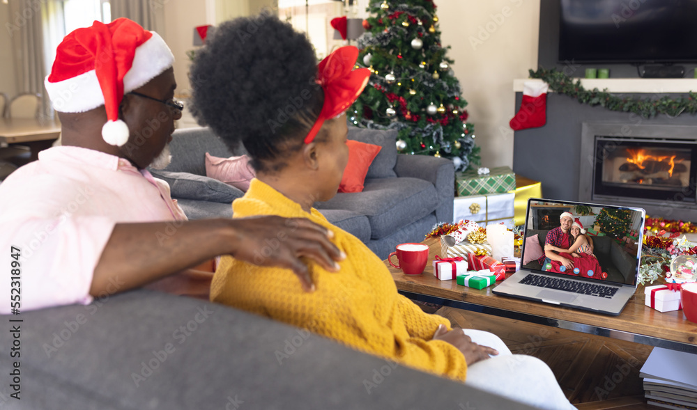 Senior african american couple having christmas video call with caucasian couple