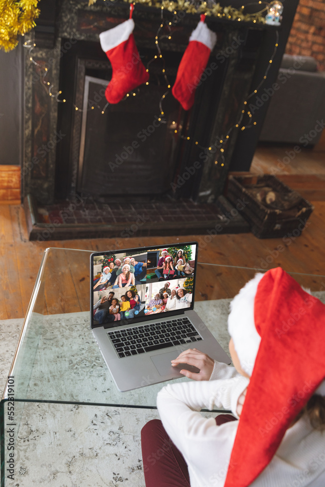 Caucasian woman with santa hat having christmas laptop video call with happy diverse friends