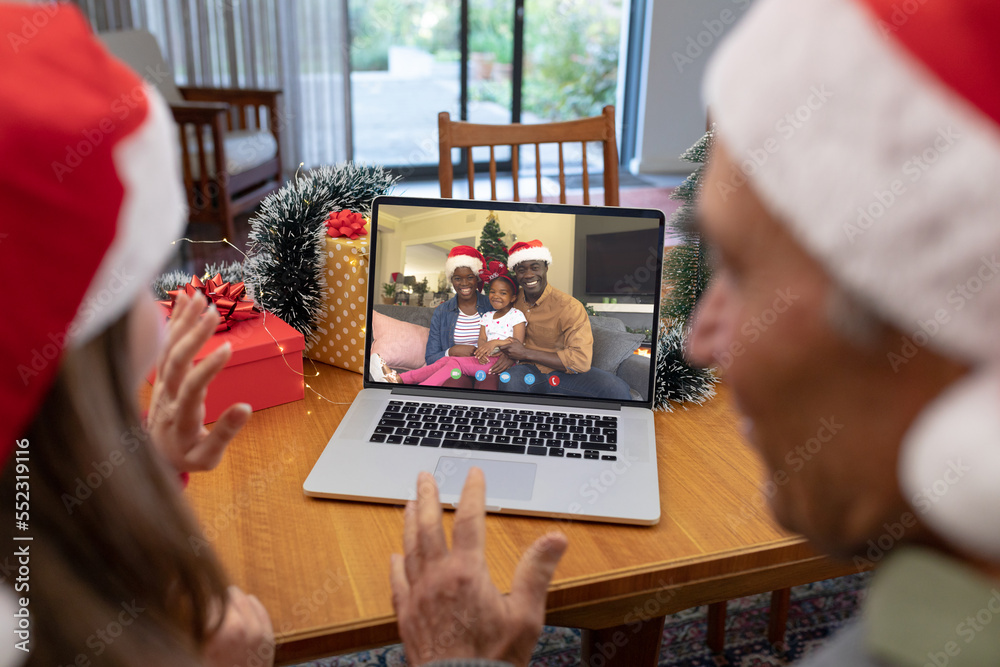 戴着圣诞老人帽的白人父女与非裔美国人家庭圣诞视频通话