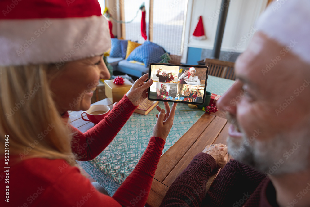 戴着圣诞老人帽的高加索夫妇与快乐的高加索朋友进行圣诞视频通话